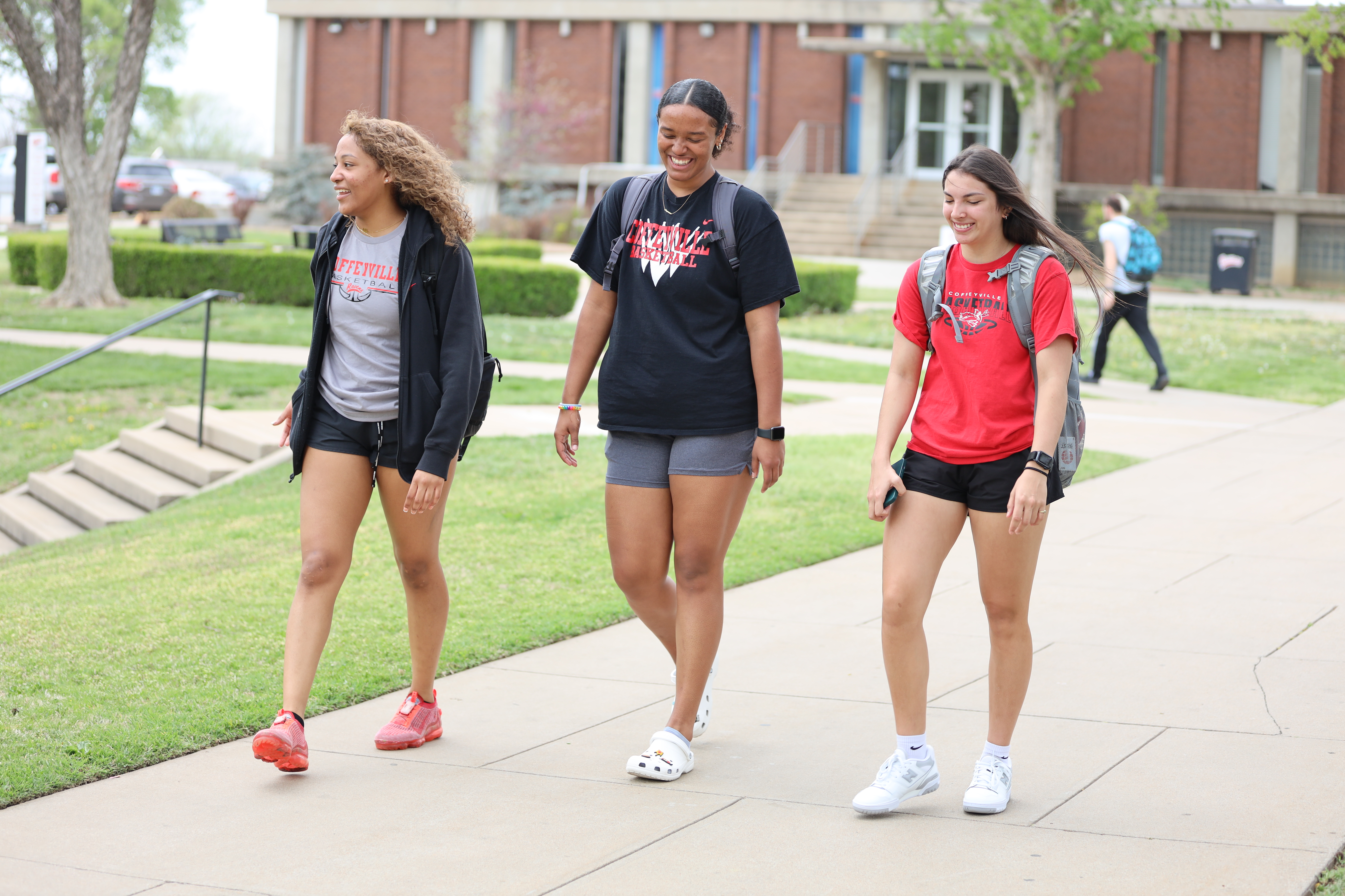 Three Students are walking through campus on there way to class.